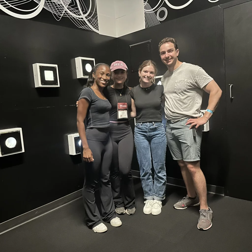 Four friends in front of a black wall with shapes